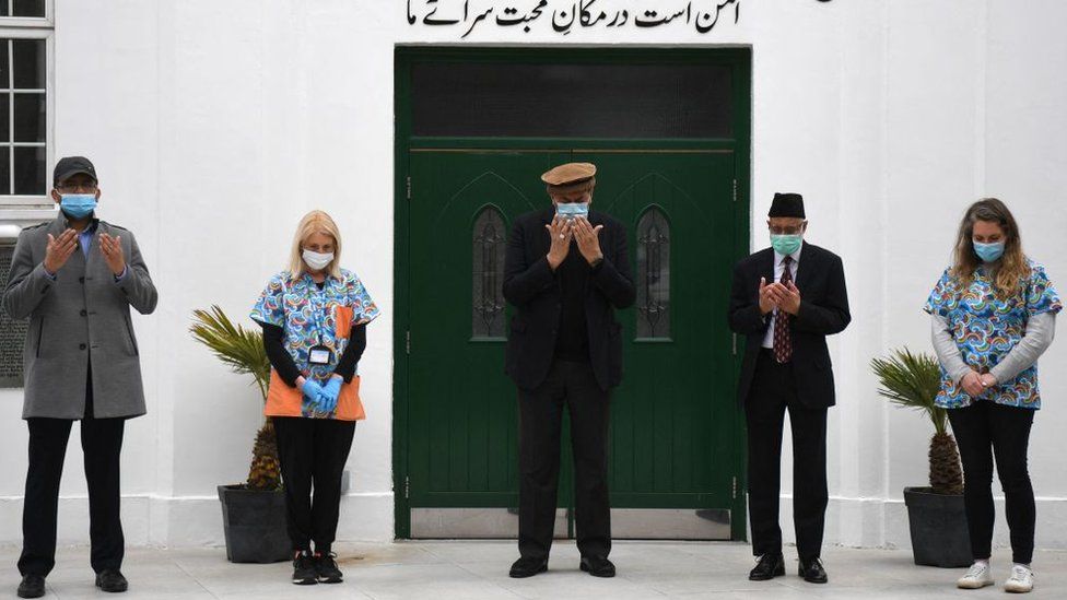 Health workers and faith leaders at the Fazl mosque vaccination centre take part in a minutes silence