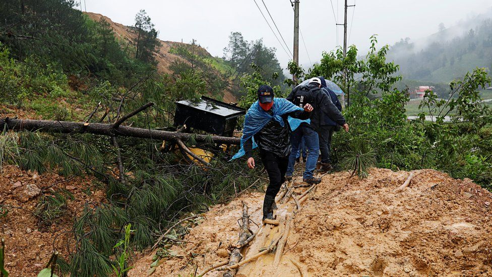 Men cross a mudslide blocking a road after the passage of Storm Eta, in Purulha, Baja Verapa