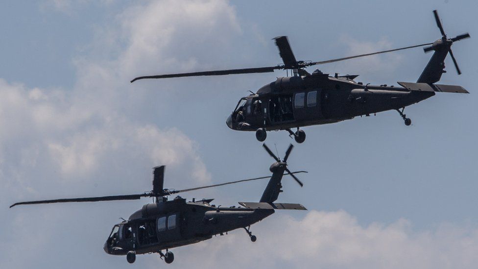 Two military helicopters fly in close formation