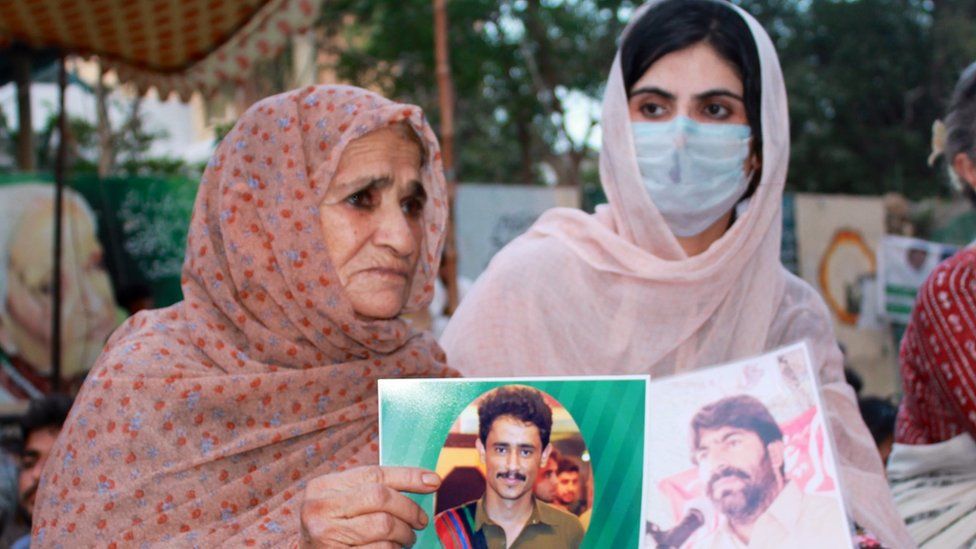Deen Baloch Sammi(right) holds up a photograph of her father, who had been missing since 2009