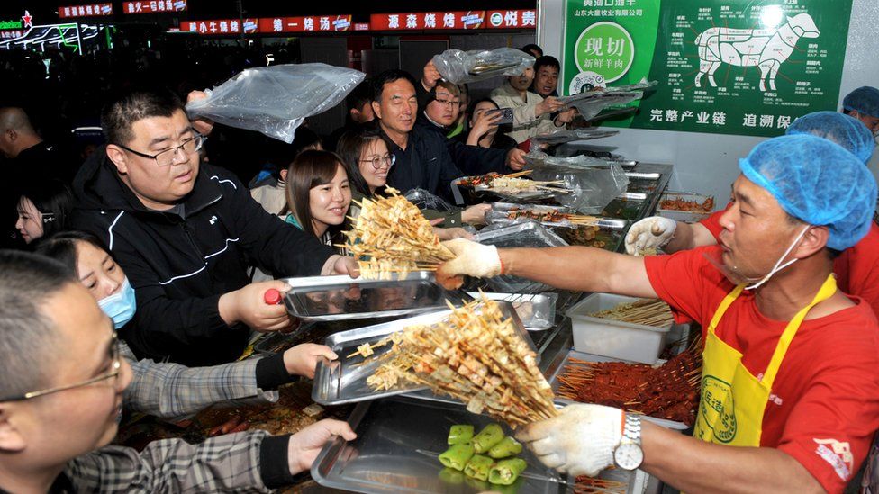 Tourists picking out meat skewers at a barbecue joint in Zibo