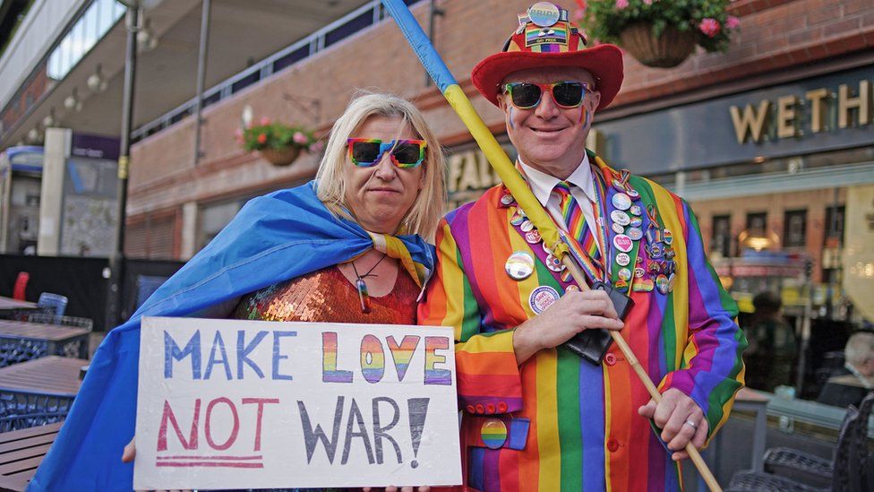 People ahead of the Pride in Liverpool parade, one holding make love, not war sign