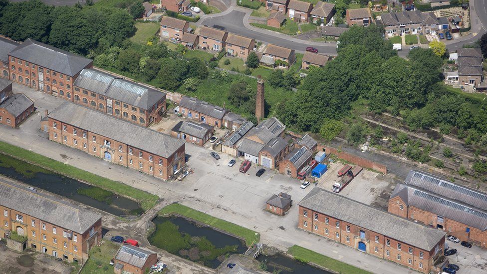 Aerial shot showing large brick buildings and a row of trees