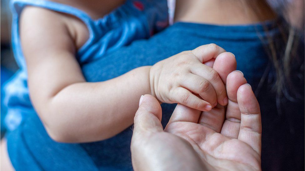 Hand of a baby in the hand of an adult