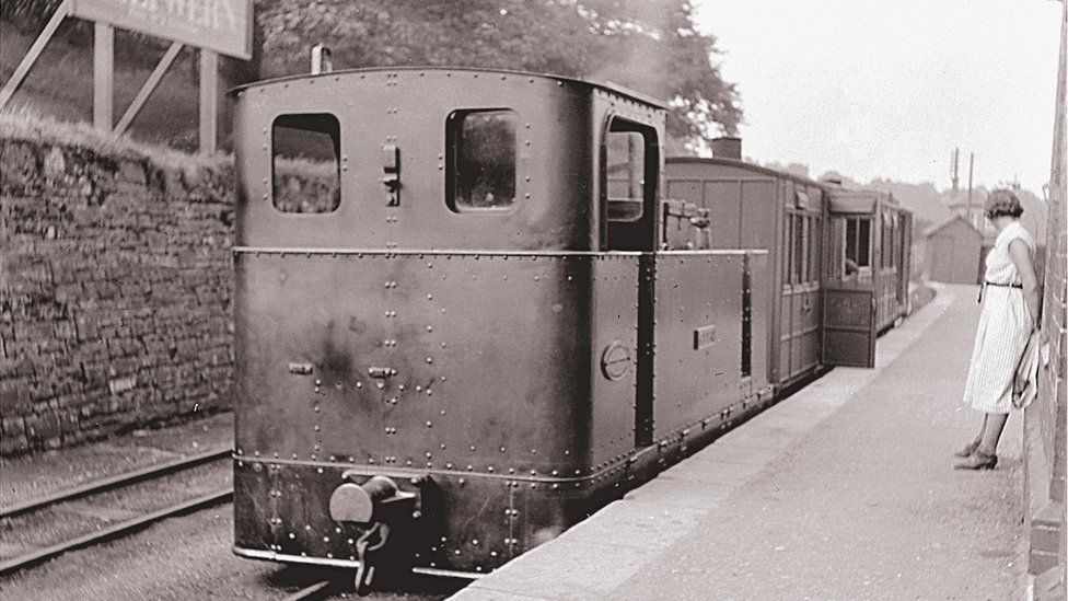 Woman waits on platform beside locomotive on the Glyn Valley Tramway at Dolywern