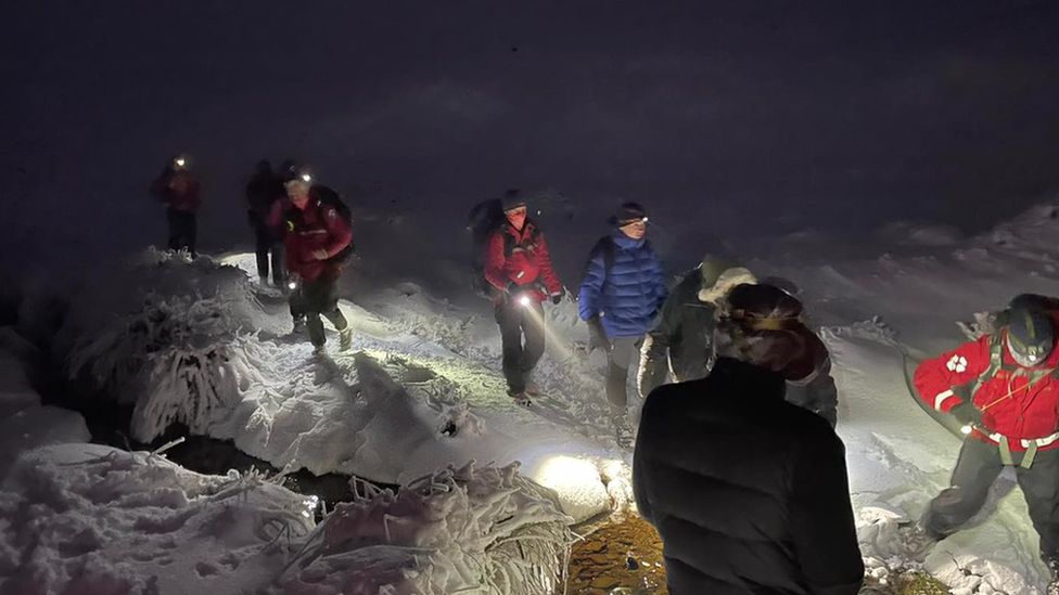 Rescuers walk through snow