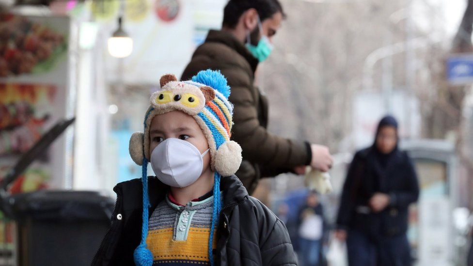 A child wearing a face mask walks on a street in Tehran on 26 February 2020