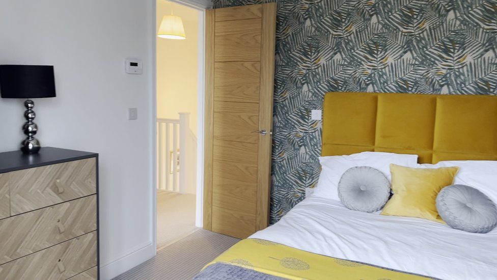 A bedroom at Bridge View with a yellow bedhead and patterned wallpaper