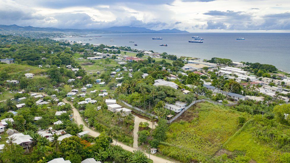 An aerial view of houses and a bay with ships in the Solomon Islands