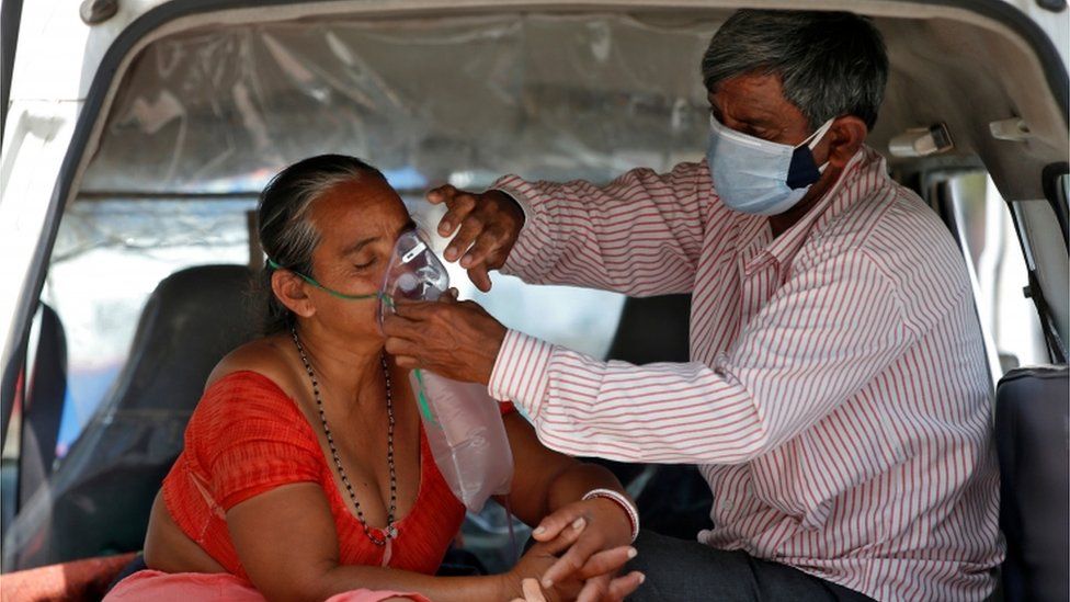 A man helps a woman with her oxygen mask