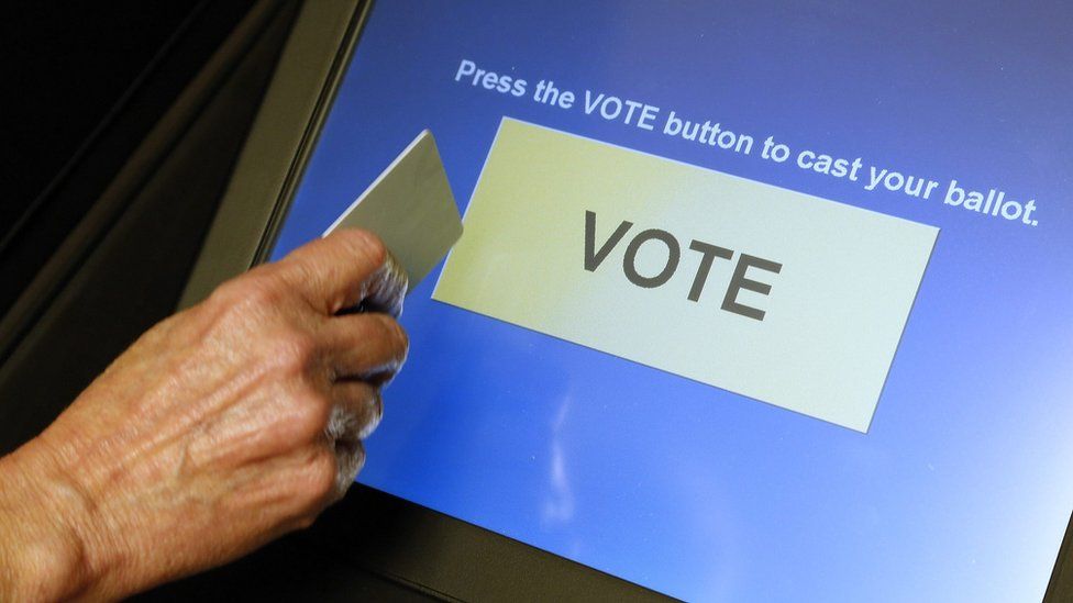 An elections official demonstrates a touch-screen voting machine at the Fairfax County Governmental Center in Fairfax, Virginia, U.S. on October 3, 2012