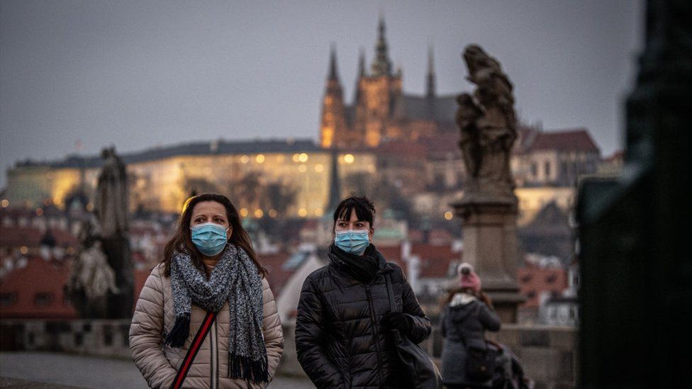 Women, wearing face masks, walk on the Charles Bridge in Prague, Czech Republic