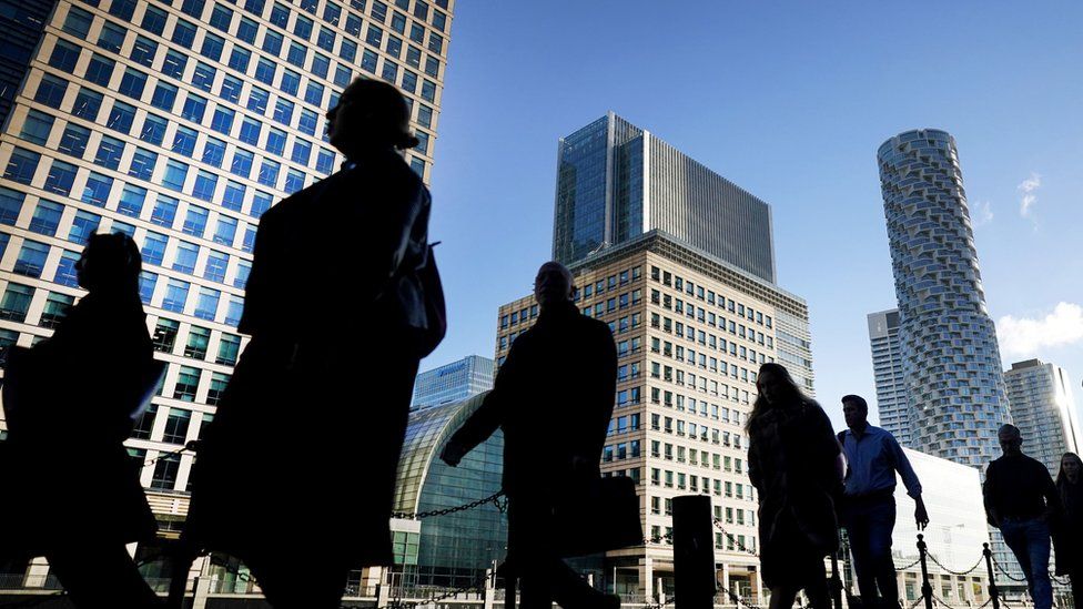 Office workers and commuters walking through Canary Wharf in London.