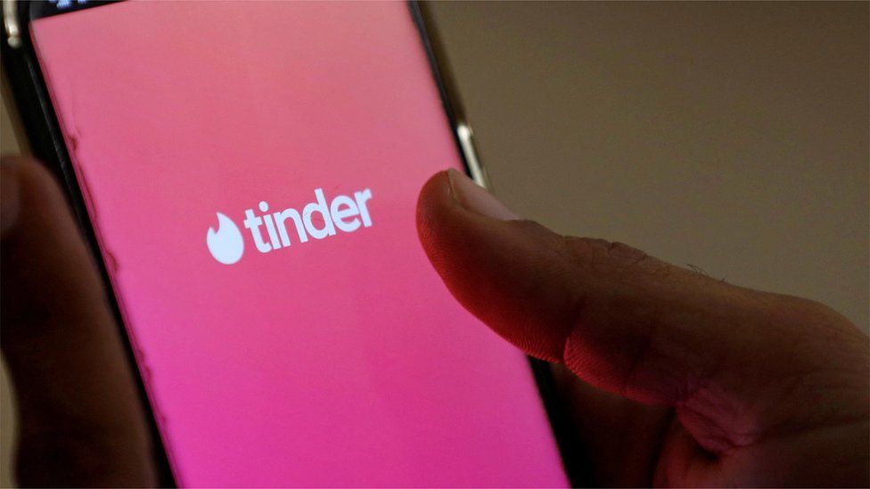 A phone with the Tinder logo on it