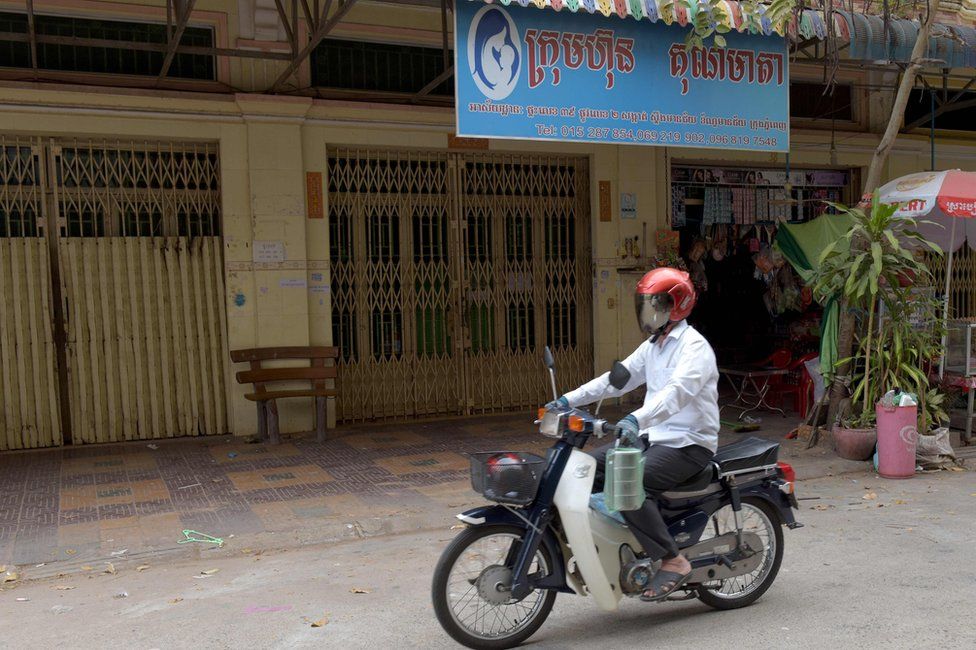 This photo taken on 16 March 2017 shows a man riding a motorbike past the offices of Ambrosia Labs in the Stung Meanchey neighbourhood of Phnom Penh
