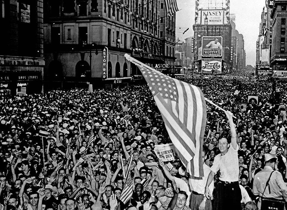 A crowd cheering with a man waving an American flag