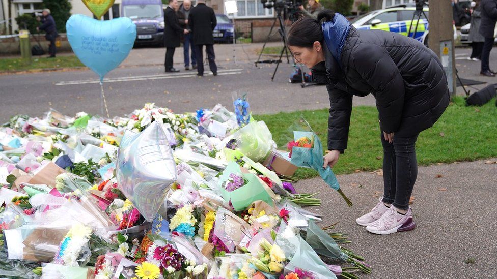 A woman leaves flowers at the scene