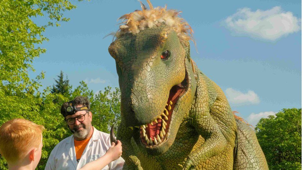 Father showing his son a dinosaur sculpture