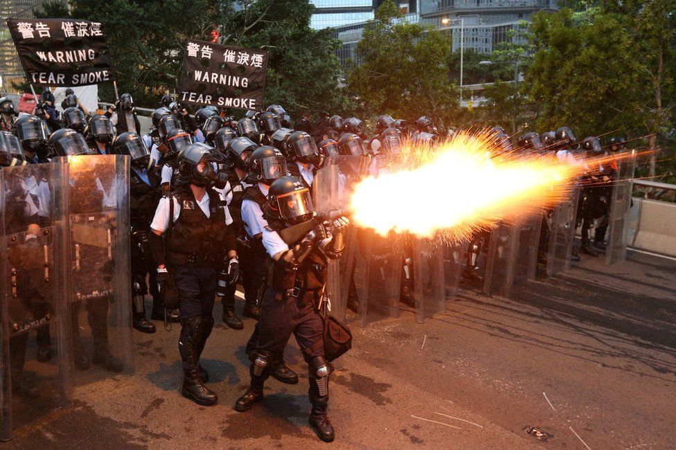 Police officers in Hong Kong fire tear gas at protesters.