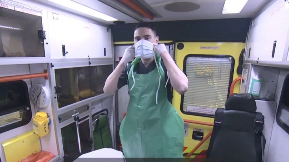 London paramedic putting on apron, mask and gloves