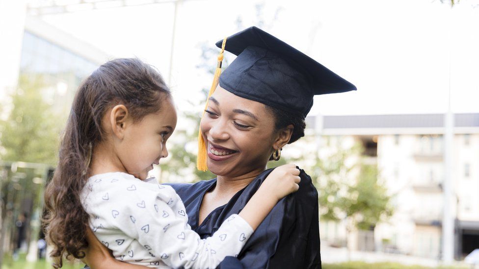 Preschool girl smiles at her mother after the graduation ceremony - stock photo