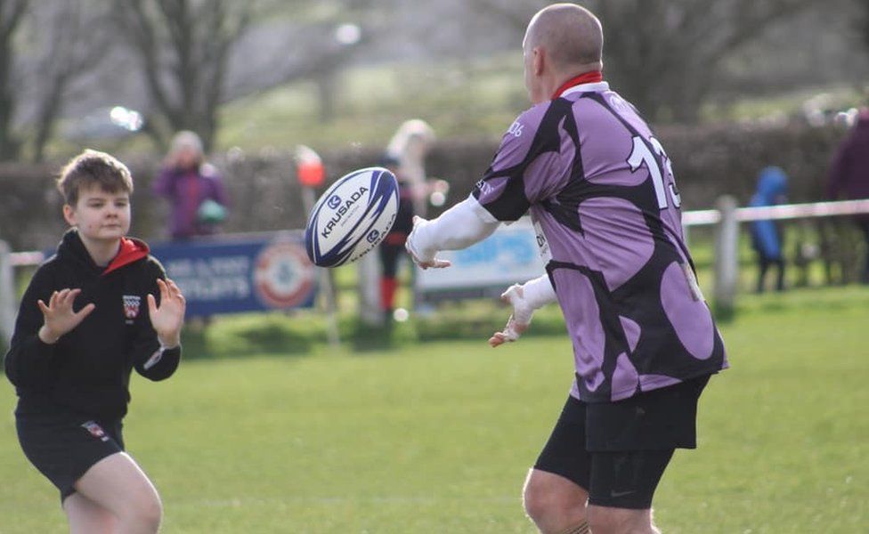 Father throwing rugby ball to his son