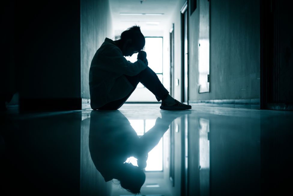 Adolescente triste sentada en un pasillo