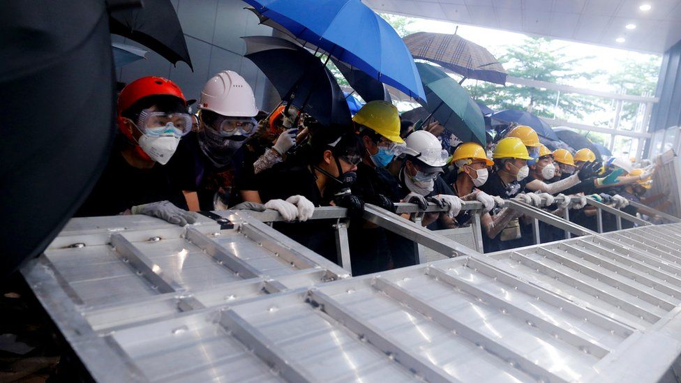 Protesters use a barricade to smash into the Legislative council building