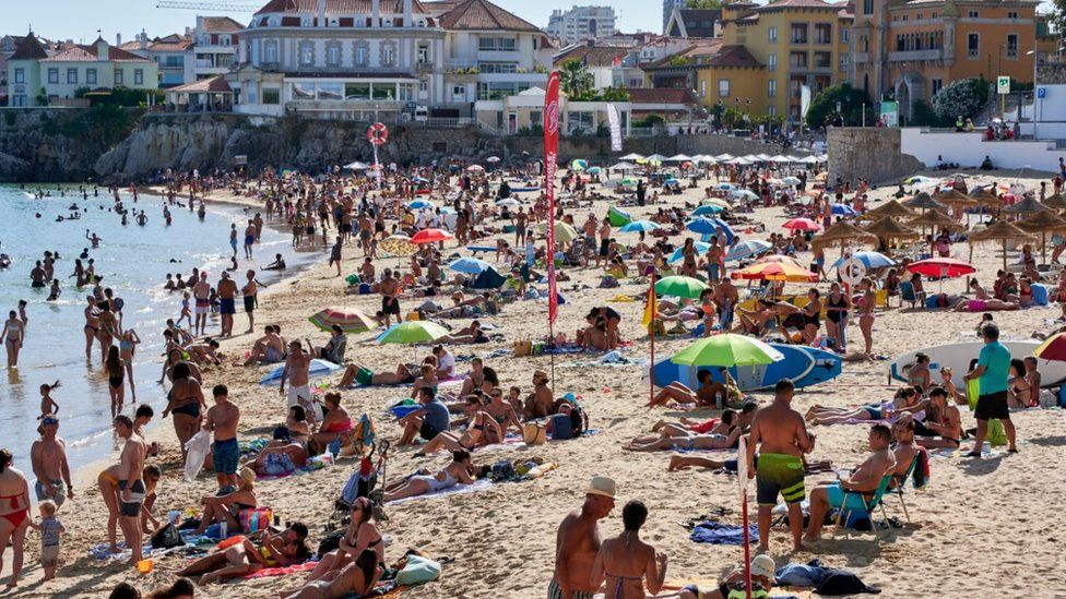 Beachgoers crowd Praia da Duquesa in Cascais, Portugal