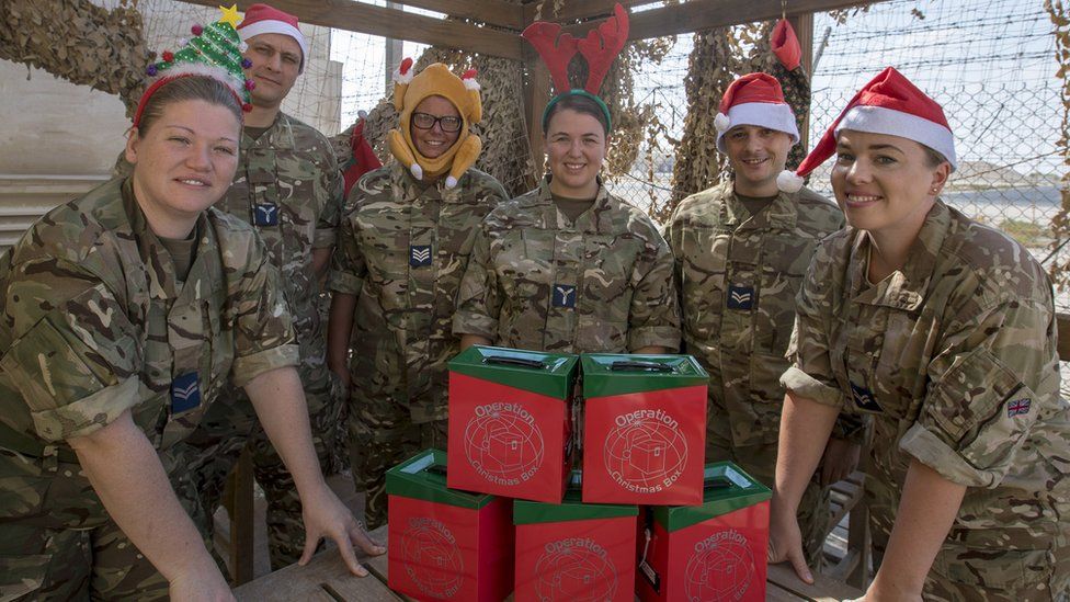 Six members of the armed forces wearing Christmas-themed headwear