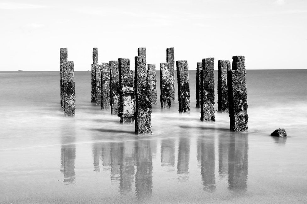 Black and white picture of stone pillars standing out of the sea