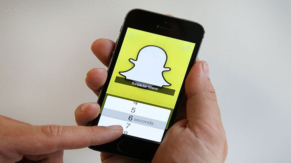 Рука держит мобильный телефон с логотипом Snapchat