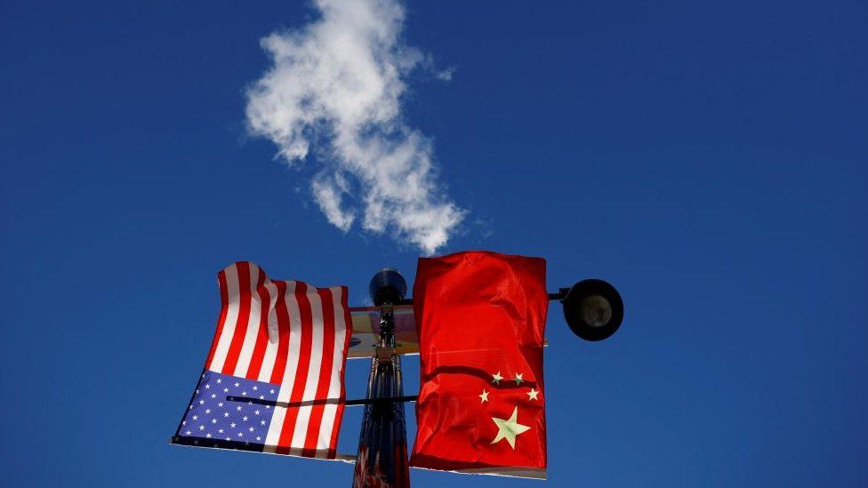 Флаги США и Китая развеваются над фонарным столбом