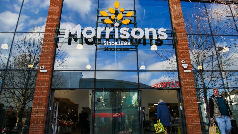 Shoppers are seen with Morrison shopping bags outside a branch of Morrison supermarket