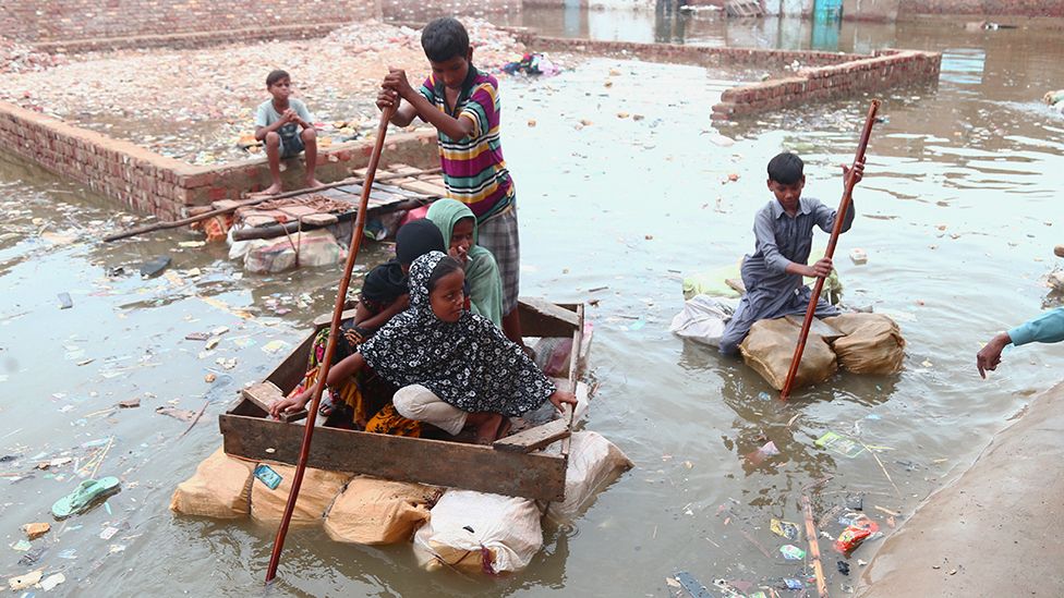 People ride an handmade boats through flooded Al Shah Colony after heavy monsoon rain hits Hyderabad, Pakistan - 26 July 2022