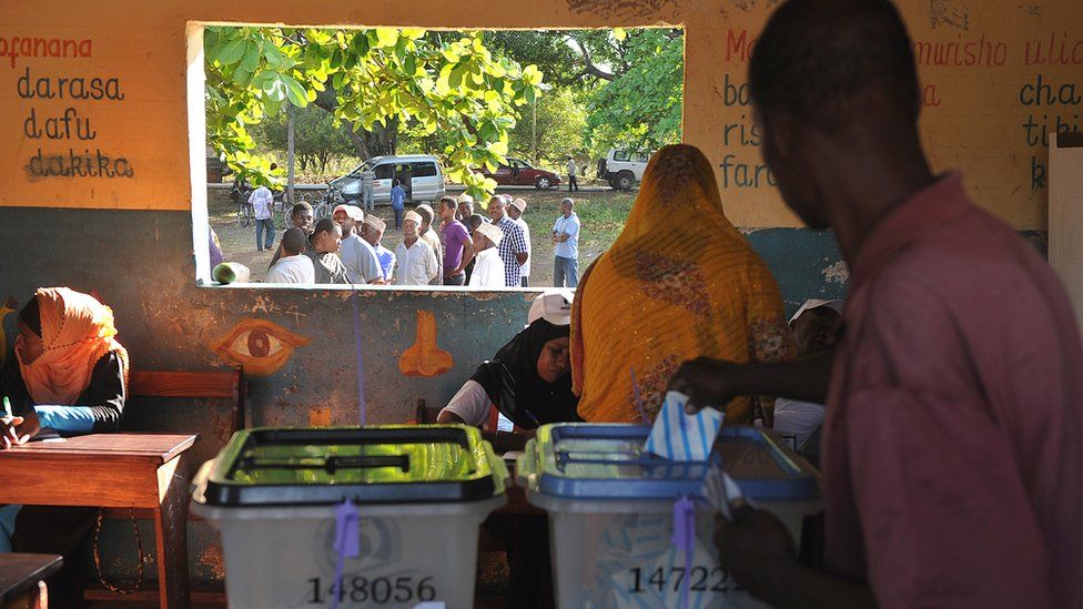 Tanzanians cast their ballots for the Tanzanian presidential elections as others queue at a polling station on 25 October 2015 in Zanzibar