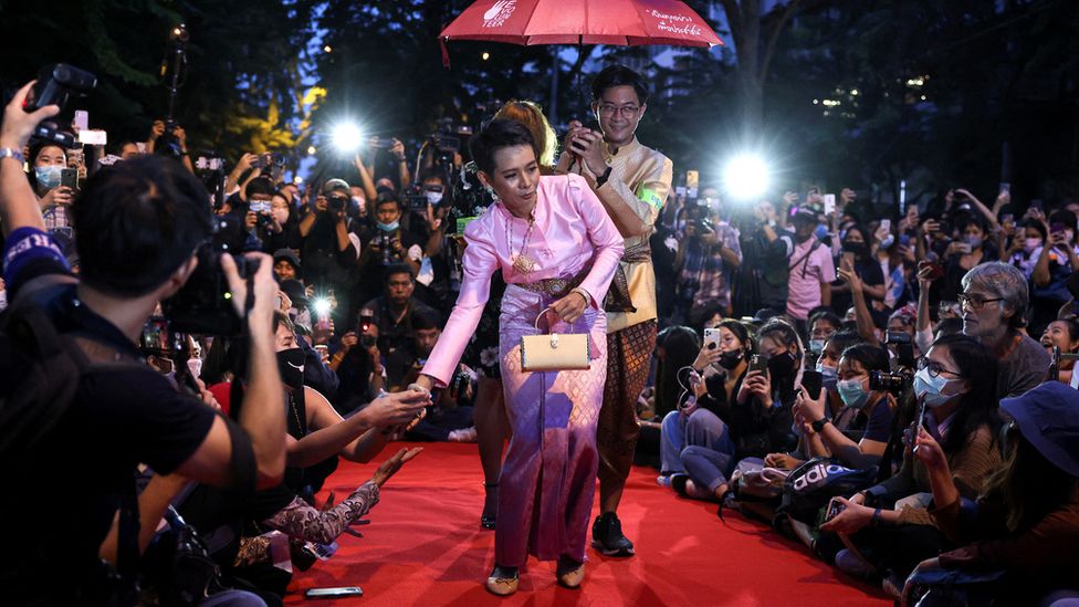 Jatuporn 'New' Saeoueng wears a pink silk dress and shakes hands with other activists on a red carpet at a satirical fashion show protest in Bangkok in 2020