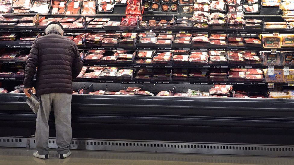 a man looks at meat in a grocery store
