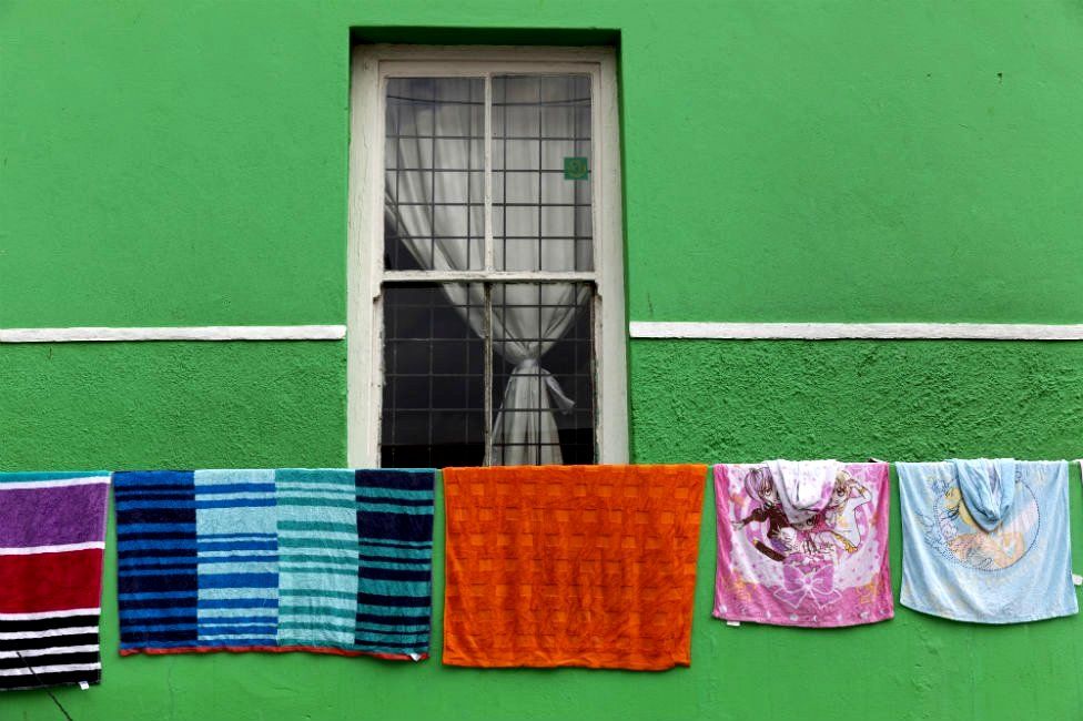 Washing hangs from a line outside a house that is painted green.