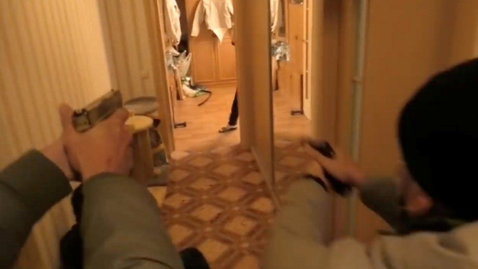 Belarusian security officers enter an apartment during a raid in Minsk, Belarus