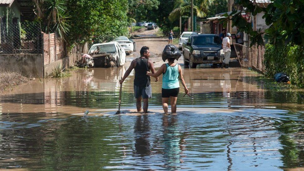 Couple wade through flooded street in La Lima, Honduras, on 8 November 2020