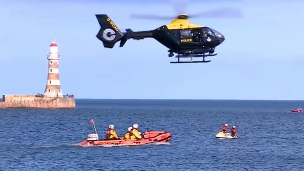 A rescue helicopter and lifeboat at the scene
