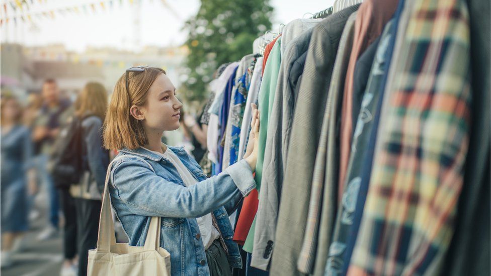 Женщина просматривает одежду на рынке