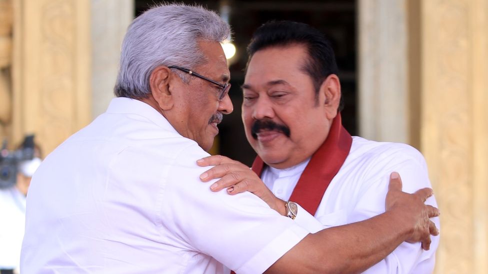 President Gotabaya Pajapaksa embraces his brother Mahindra, who is the prime minister, at Mahindra's swearing-n ceremony