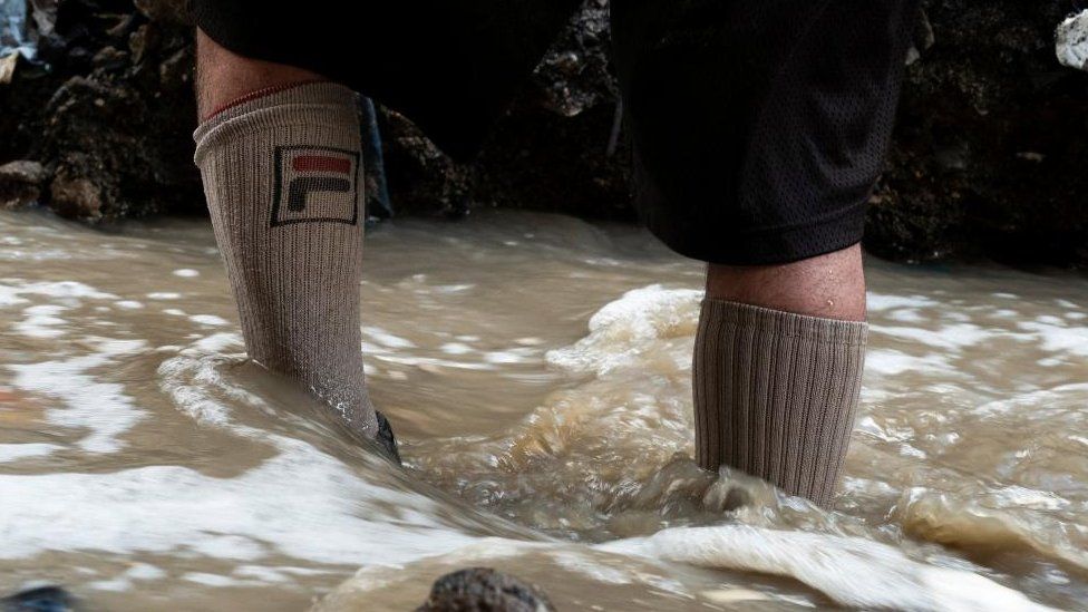 A man searches for scrap metal in the polluted waters of the Las Vacas river