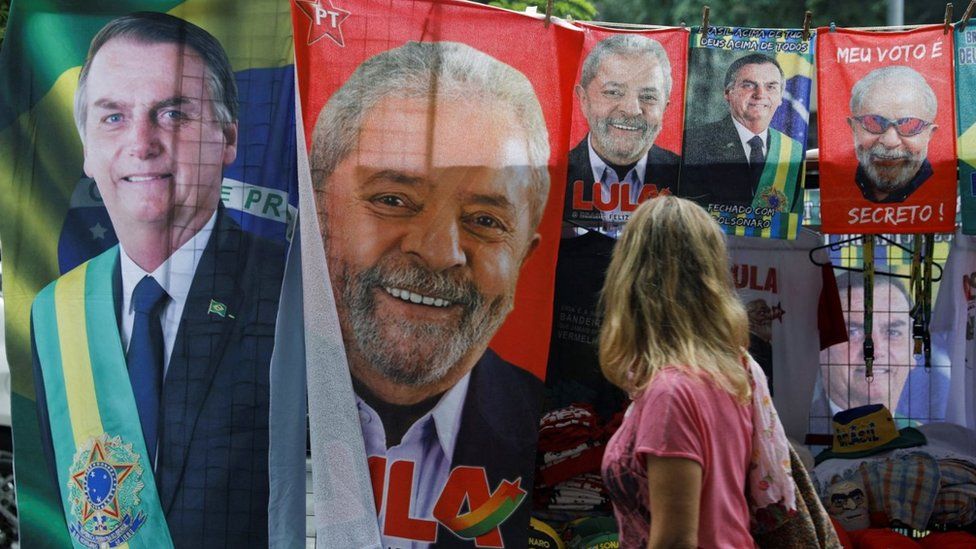 A woman looks at displayed towels and presidential campaign materials depicting Brazil's former President Luiz Inacio Lula da Silva and Brazil's President Jair Bolsonaro