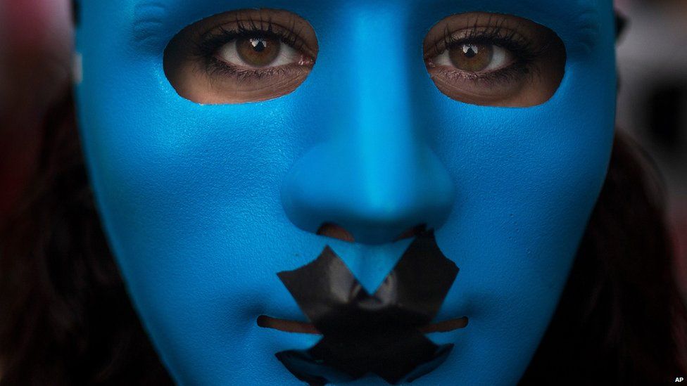 A protestor wears a mask with a gag as she marches against the Public Security Law in Madrid, Spain, Tuesday, June 30, 2015.