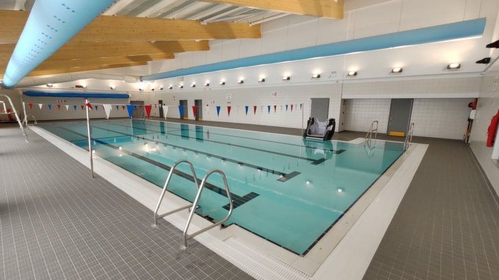 An indoor swimming pool with lanes and bunting hung across the room.
