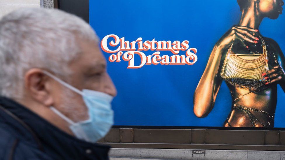 Man wearing a face mask walking past Oxford St Christmas displays