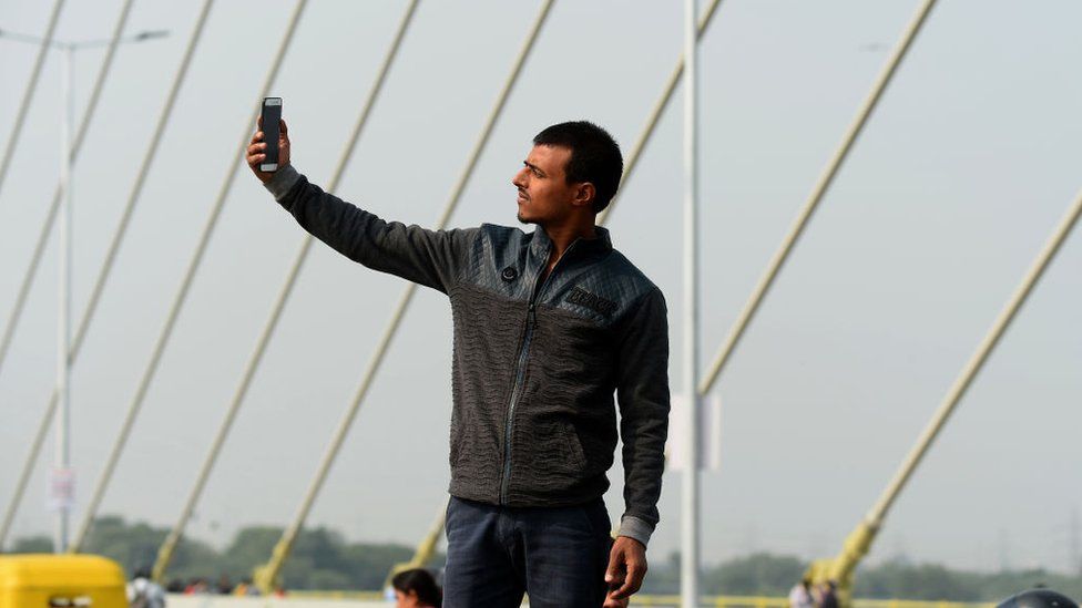 A man taking a selfie with the signature bridge in the background